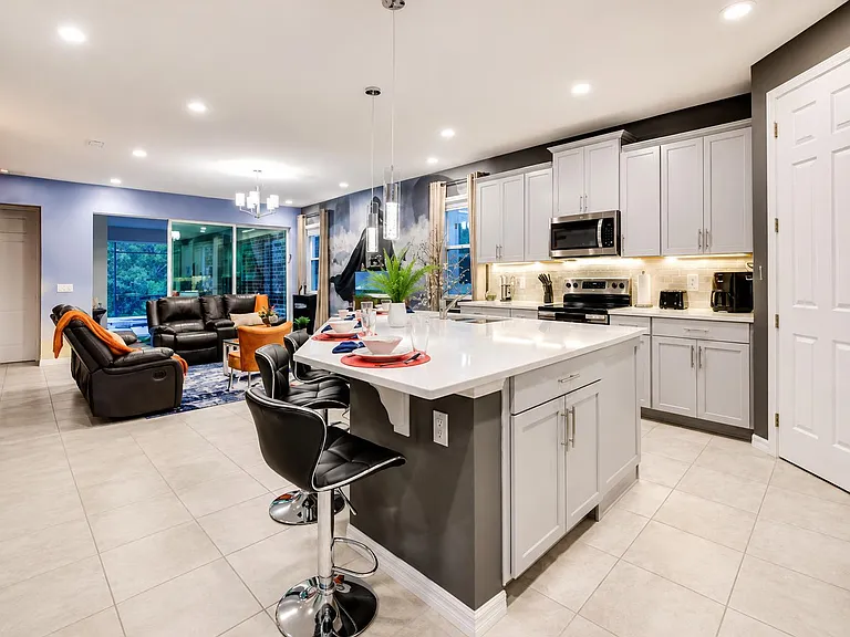 Open-concept kitchen with a large island, bar seating, and stainless steel appliances, flowing into the main living area.