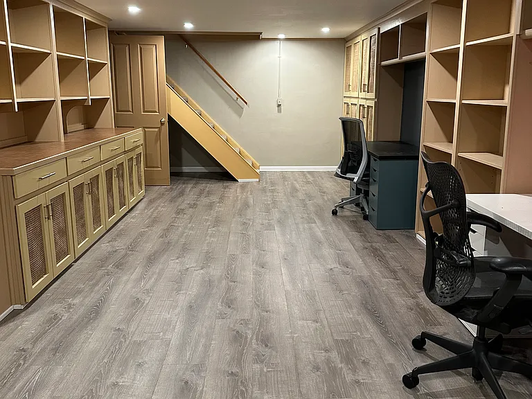 Basement with able built-in storage space and two desks.