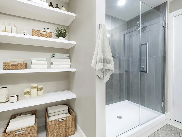 Sleek glass-enclosed showers in select homes offer a spa-inspired retreat with modern finishes and built-in shelving for effortless organization.