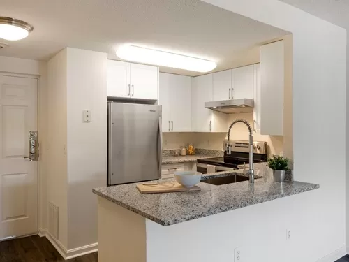 Renovated Package III kitchen with white cabinetry, grey granite countertops, stainless steel appliances, and hard surface flooring - eaves Washingtonian Center