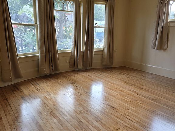 Large living room with new blackout curtains, ceiling fan, sanded refinished original hardwood floors. It's gorgeous, unique, 1907 with pocket doors
