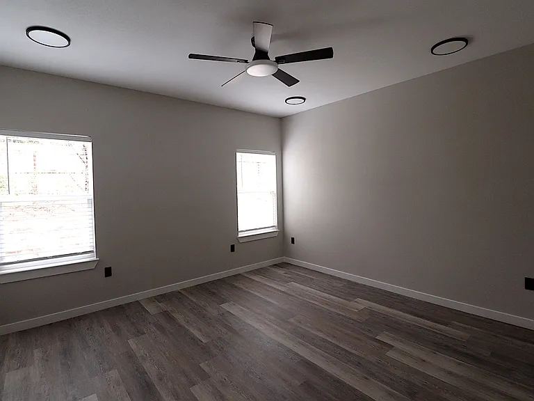 Bright primary bedroom with two windows, abundant natural light, modern flooring, and a stylish ceiling fan.
Bright primary bedroom with two windows, abundant natural light, modern flooring, and a stylish ceiling fan.