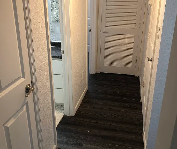 Hallway view from the ensuite door.
Left side: linen closet, guest bathroom, not-ensuite bedroom.
Right side: access to the living room, laundry closet.
At the rear: mechanical room.