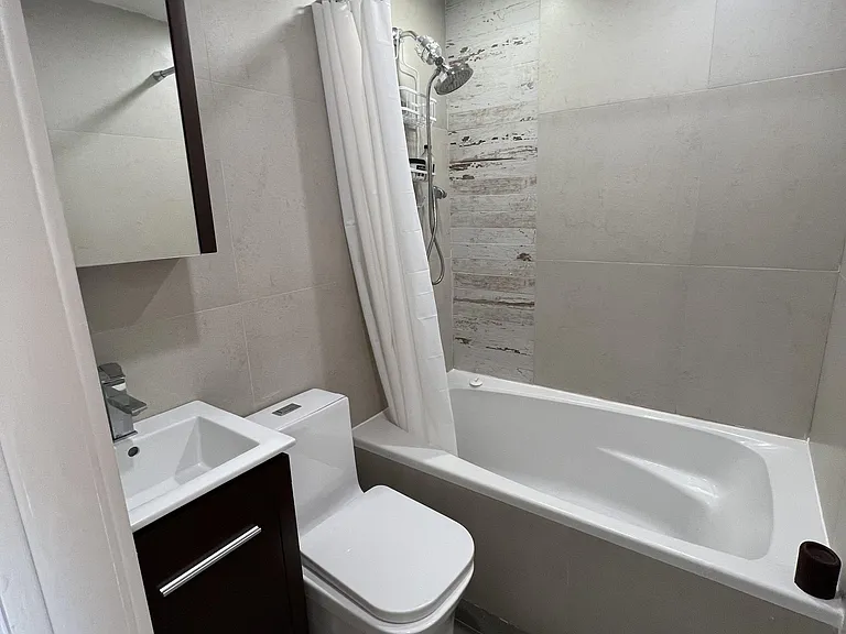 Full bathroom with tub-shower combo, tiled surround, modern vanity with mirror cabinet, and recessed lighting.