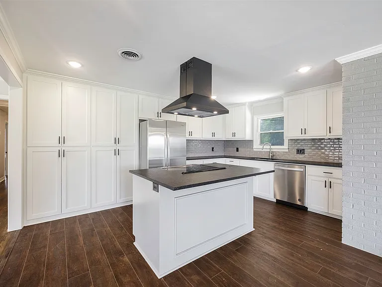 Kitchen featuring a center island, crown molding, appliances with stainless steel finishes, island exhaust hood, and tasteful backsplash