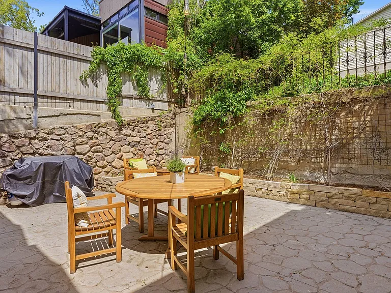 Private back patio with mature trees and entrances from both dining room and kitchen. The huge additional 4 car garage is also visible to the right.