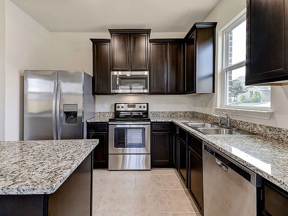Plenty of space in this kitchen with sprawling granite counters and tall designer wood cabinetry.