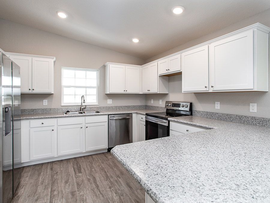Open kitchen with shaker-style cabinets, SS appliances, and vinyl plank flooring - Photos from a hom
