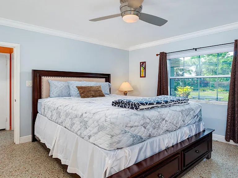 Spacious bedroom with a large window, ceiling fan, and ample space for a full furniture setup.