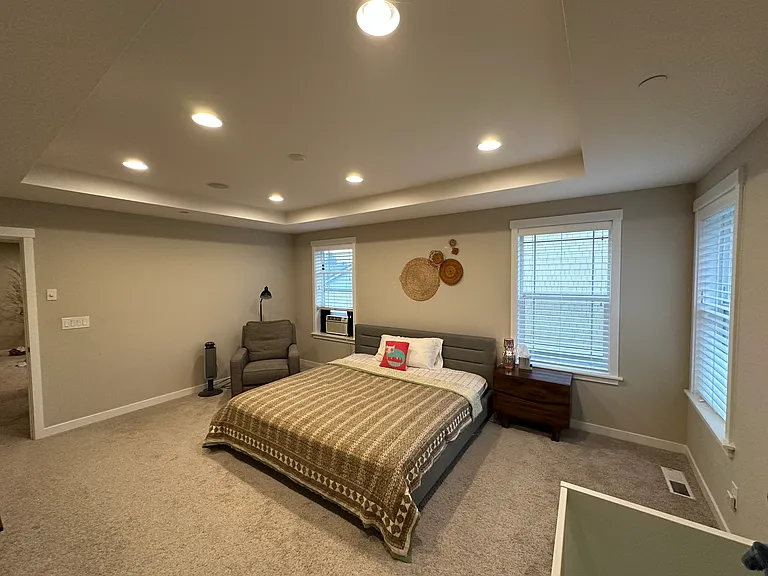 Primary room with King bed, side tables and crib at the bottom right of the photo