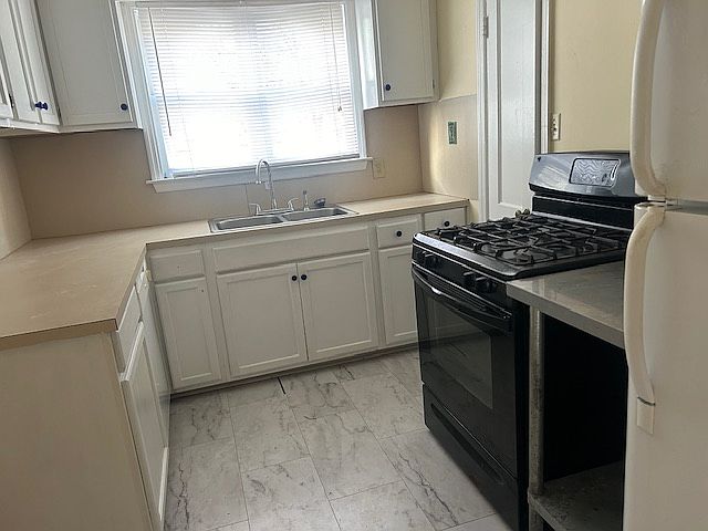 The kitchen has a newly marbleized tile floor, new faucet, freshly painted cabinets, gas range and electric oven, refrigerator, and a pantry.