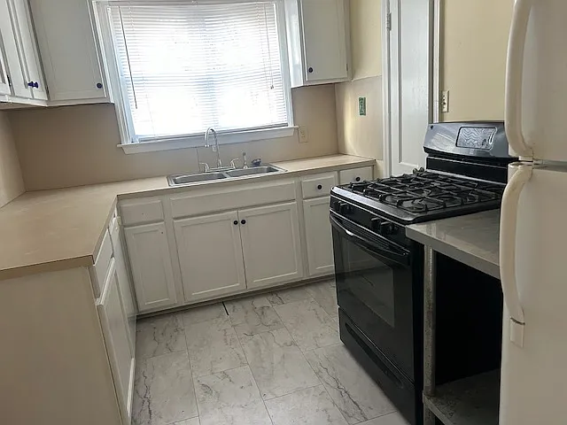 The kitchen has a newly marbleized tile floor, new faucet, freshly painted cabinets, gas range and electric oven, refrigerator, and a pantry.