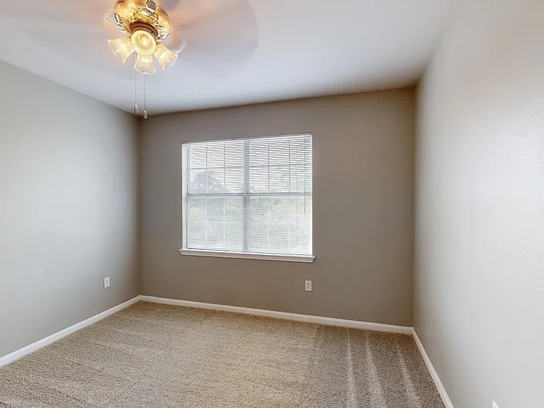 Spacious apartment bedroom with plush carpet flooring.