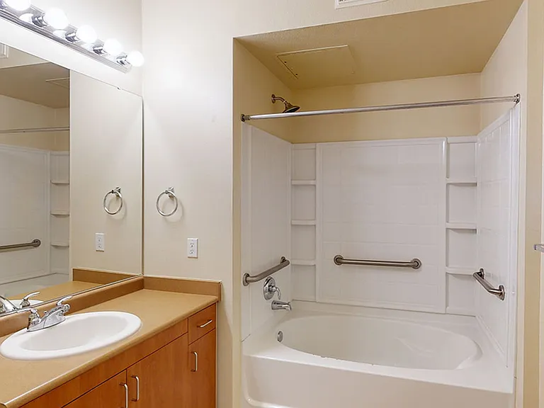 Apartment bathroom with large soaking tub and wood-style flooring.