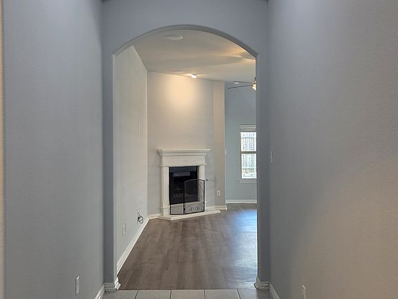 Corridor featuring arched walkways, tile patterned floors, and a raised ceiling