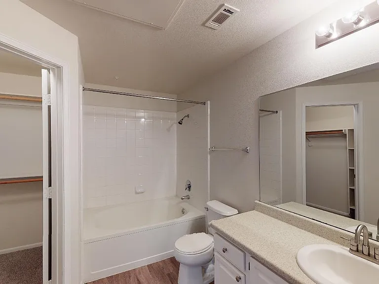 Apartment bathroom with wood-style flooring.