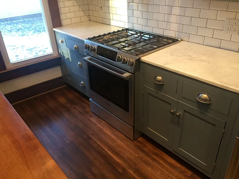 duel fuel, gas / electric range. marble countertops, to the right of the stove are two pull out pots and pans drawers