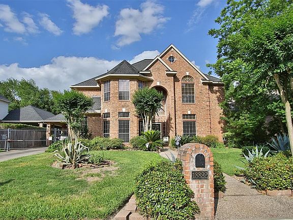 18222 Mountain Spring features a brick facade, mature landscaping, beautiful curb appeal, and an automatic driveway gate