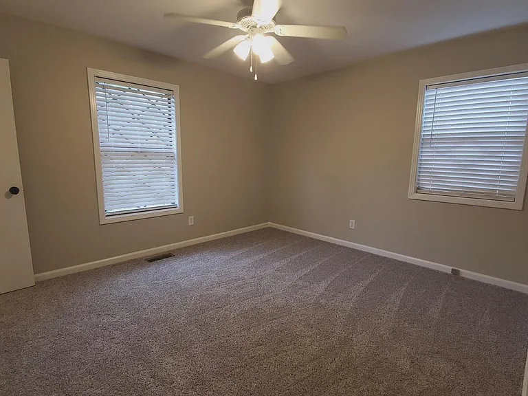 Primary Bedroom with new carpet, blinds, neutral colors, ceiling fan.