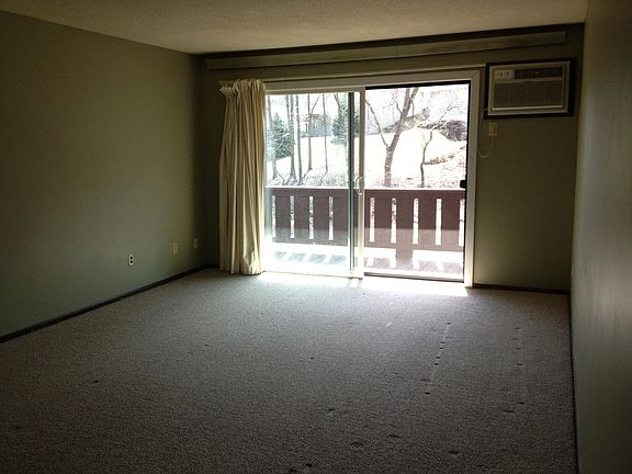 living room with balcony and through wall AC