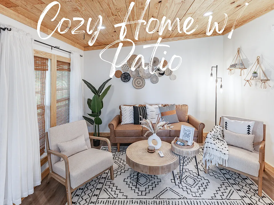 The cozy living room features distinctive boho decor in a modern, open floor plan. A wall-mounted TV complements the inviting and stylish ambiance.