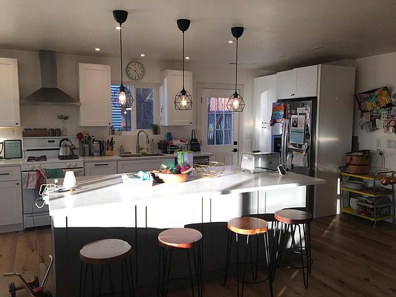 Newly remodeled kitchen with large solid surface island, oven, and new stainless steel fridge, sink, and dishwasher.