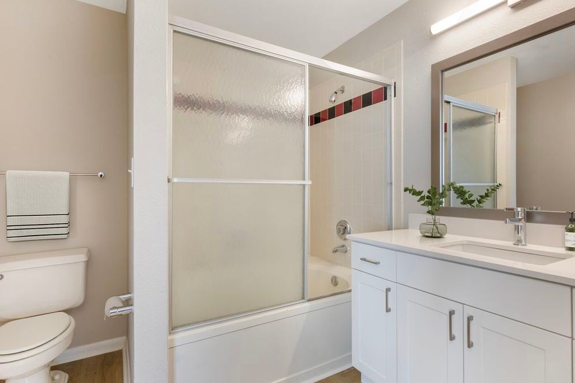Renovated Package I bath with white speckled quartz countertop, white cabinetry, and hard surface flooring