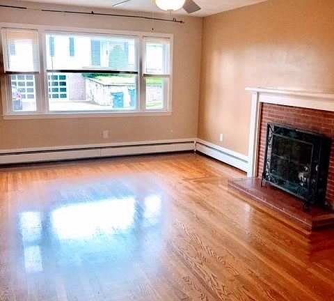 Large living room has hardwood floors, a large picture window and a gas fireplace.