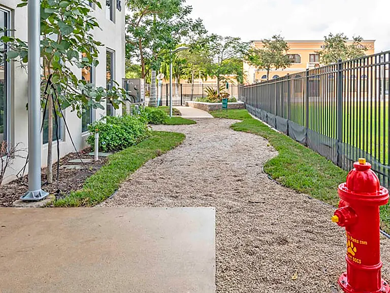 Luxury apartment community dog run with fenced pet area and landscaped walking path