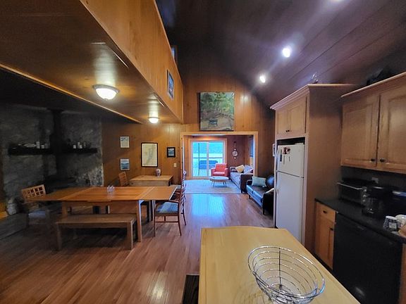 Kitchen featuring wood walls, lofted ceiling, light wood-type flooring and light brown cabinetry