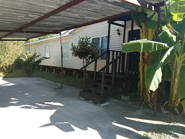 Back of the double wide mobile home with carport.