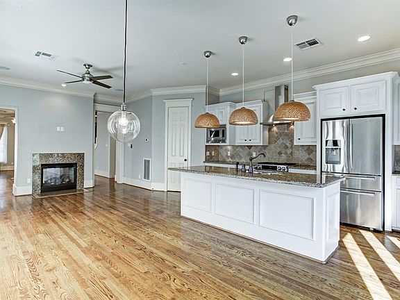 Unfurnished kitchen. Note the granite counters, tile backsplash, custom white cabinetry, and huge island breakfast bar.