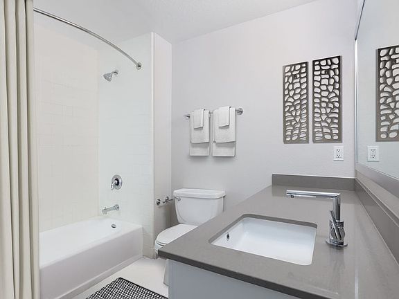 Renovated Phase I bath with quartz countertops and white cabinetry