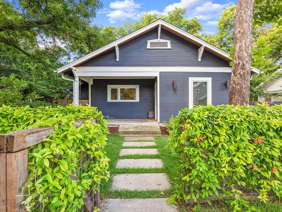 Front of the house. Fenced in front yard. Beautiful trumpet vines throughout the fence