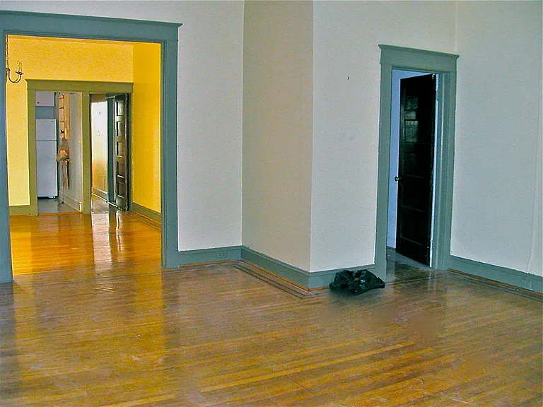 Living room toward dining room (left) and small bedroom (right). Doors in rear left open to hallway, large bedroom, and bathroom.