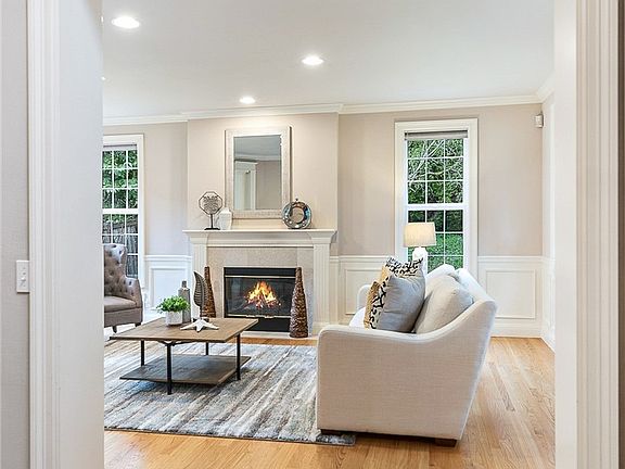 To your right off the foyer, warm hardwoods and 3 walls of windows invite you to cozy up to the wood-burning fireplace. 