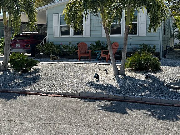 Front of home- seashell landscape with beautiful established palms and a front patio