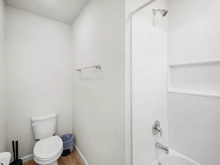 Clean full bath featuring a tub/shower combo with tile surround, built-in niche shelving, and easy-care flooring.