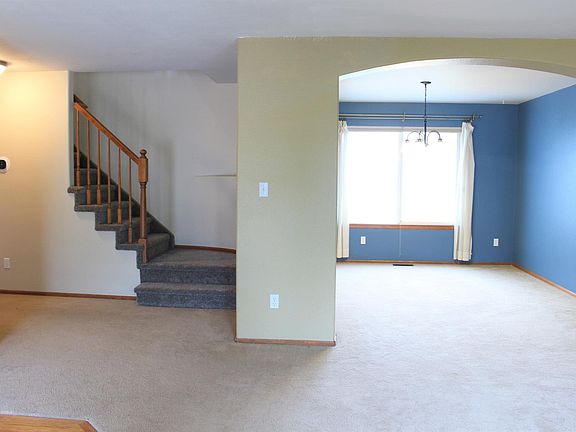Entry and front room. Main hall and half bath to left with access to living room and garage. Center: stairs to second level. Right: Front room and Dining room with kitchen access.