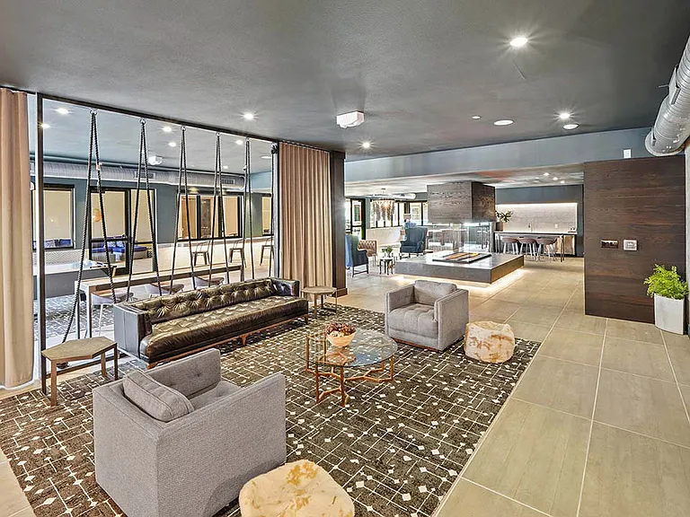 Entertainment lounge with tile floor, comfortable seating, and large TV.