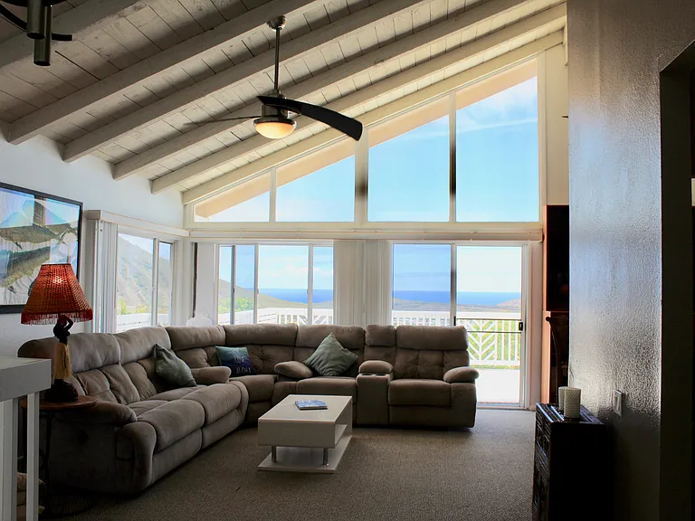 Living room with high ceilings and sweeping ocean/mountain views.