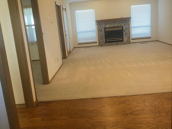 Living room with ceiling fan and lots of recessed lighting. First opening left to kitchen, next 2 to dining room, 3rd to sunroom. Bedrooms and utility are down hall to right.