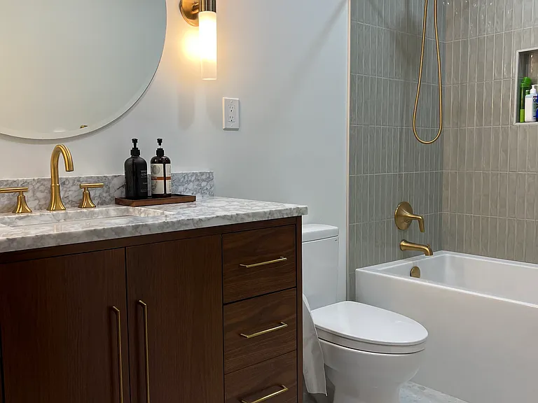 Main-level guest bathroom with soaking tub, heated floors, Kohler faucets, and marble topped vanity.