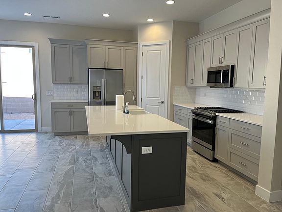 Kitchen with a large island, oversized farm-style sink, gas cooktop, new refrigerator and upgraded cabinets with slow closing feature.