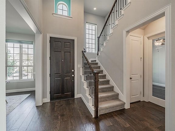 Foyer entrance with stairs, a high ceiling, baseboards, and dark wood-style flooring