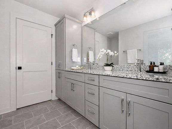Spacious master bathroom featuring a large double vanity with granite countertops and sleek grey cabinetry.