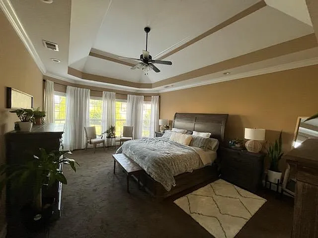 Elegant Master bedroom featuring tray ceilings and abundant windows.