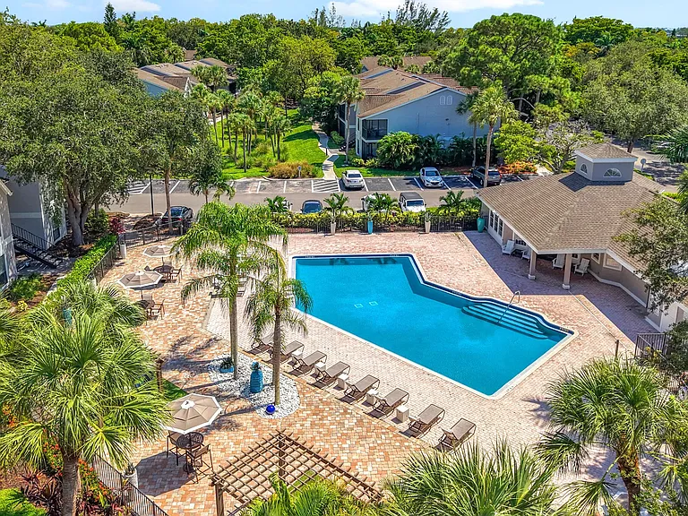 Discover an aerial perspective of River Reach's inviting amenitiesresort-style pool, lounge seating, and lush landscaping in the heart of Naples.