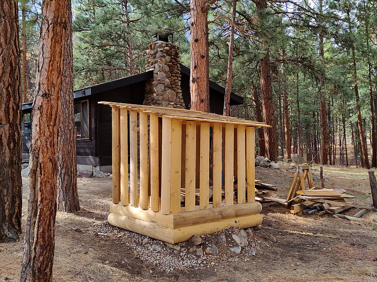 Firewood bin to the east holds approximately 1 cord of split stacked firewood. Area for gardening tools too, all covered.