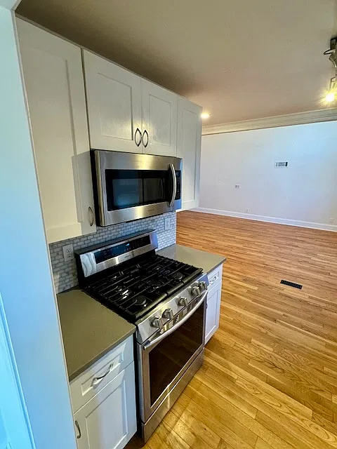 Galley Kitchen with stainless steel gas stove and microwave